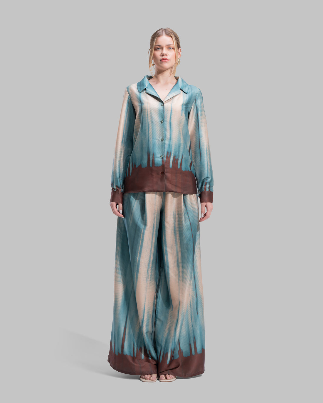 A long-sleeved button-down shirt featuring a teal and cream gradient print with a dark brown hem.