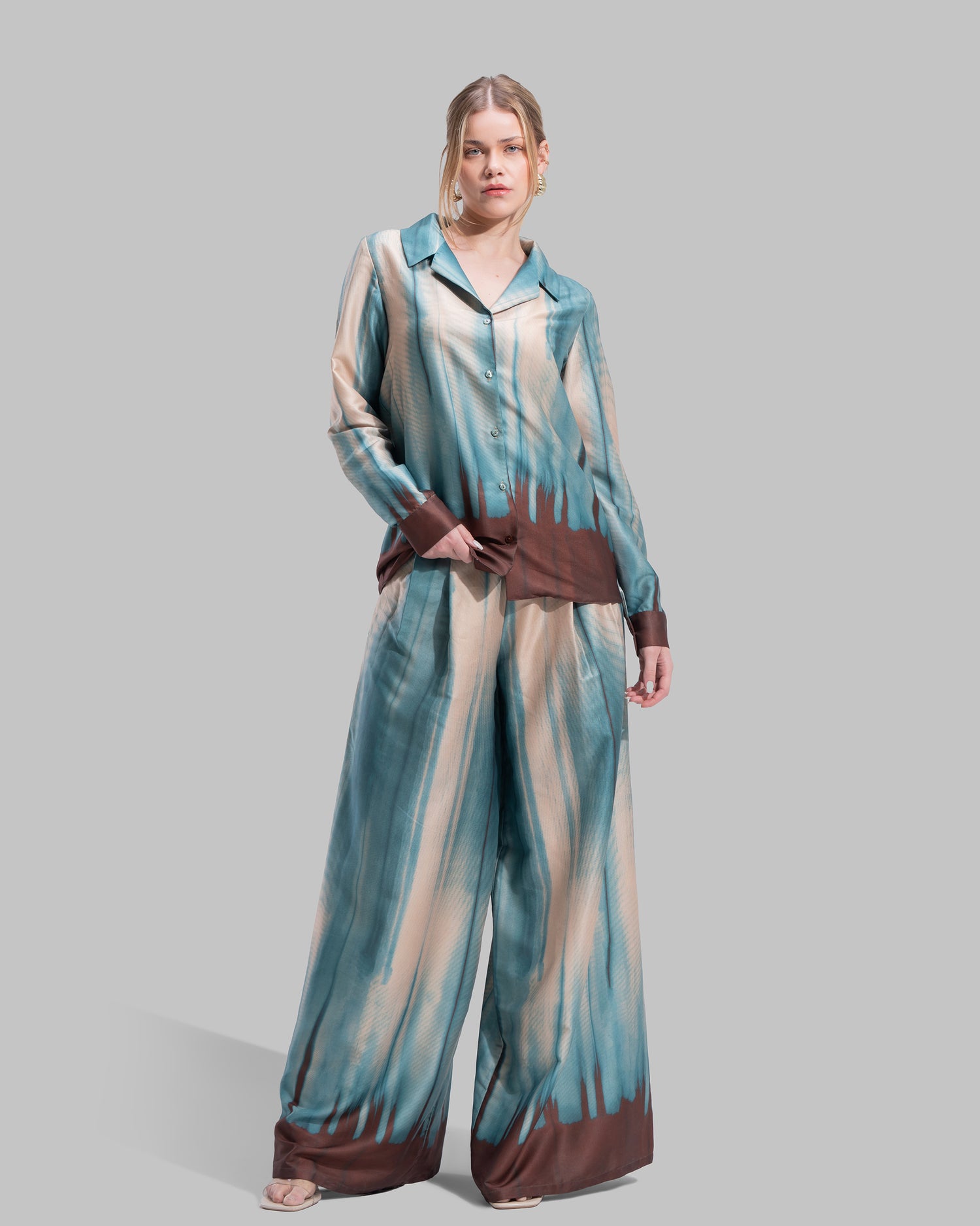 A long-sleeved button-down shirt featuring a teal and cream gradient print with a dark brown hem.
