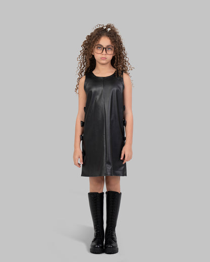 فستان مريلة من الجلد مزين بفيونكة جانبية.